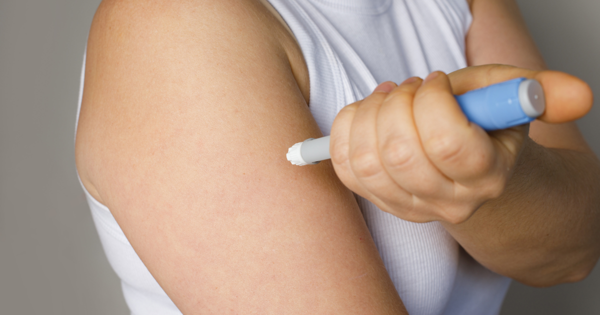 Woman demonstrating Ozempic injection technique with pen injector on abdomen in clean, well-lit setting